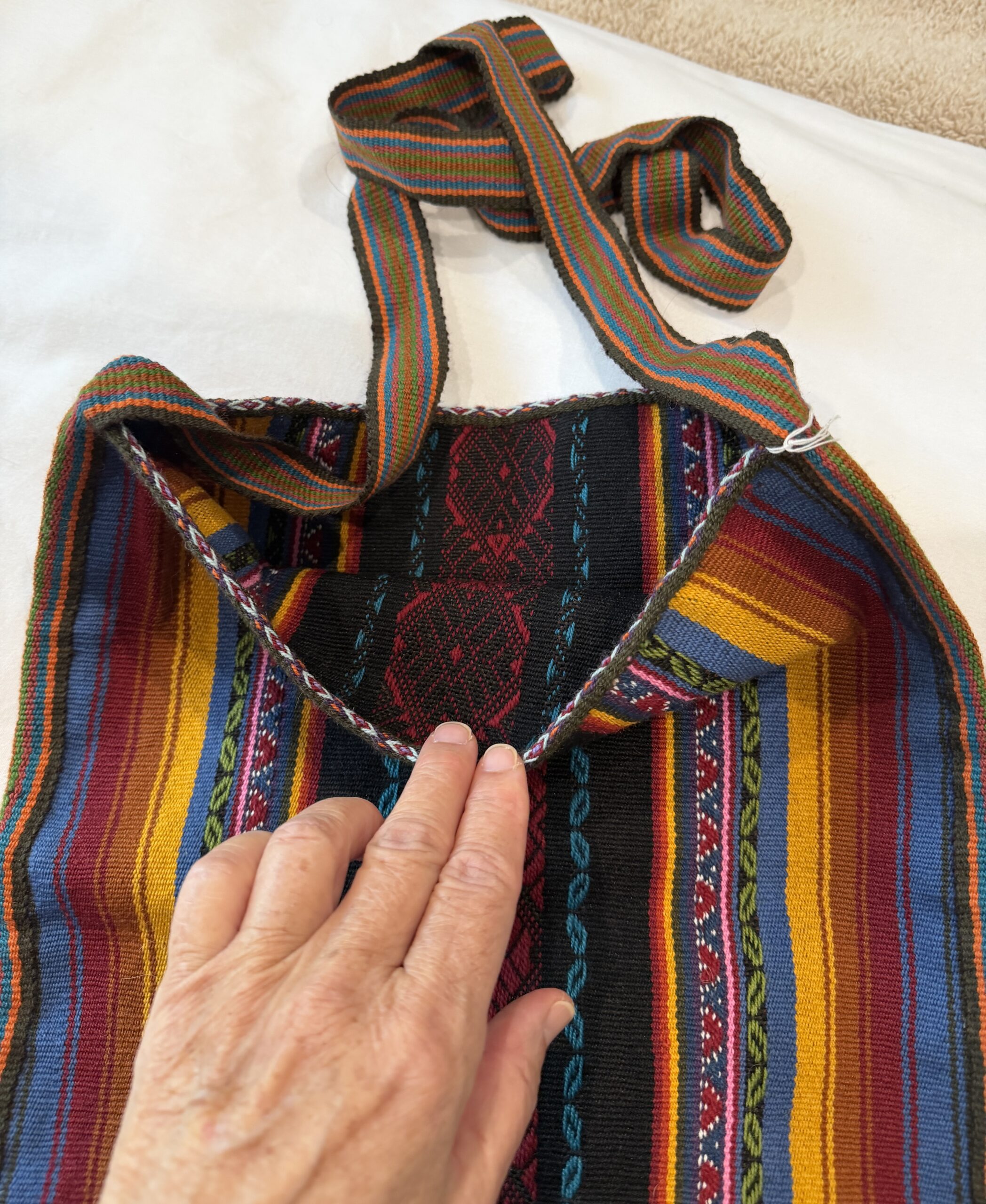 Handwoven Peruvian llama handbag featuring colorful Andean striped textile with traditional geometric weaving and an adjustable shoulder strap.